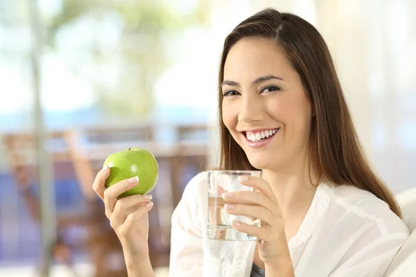 Ευτυχισμένη γυναίκα κρατώντας ένα μήλο και ένα ποτήρι νερό — Φωτογραφία Αρχείου