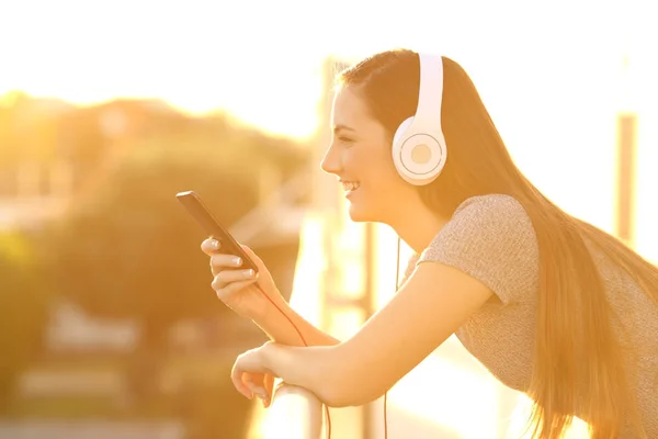 Perfil de uma garota feliz ouvindo música em uma varanda — Fotografia de Stock