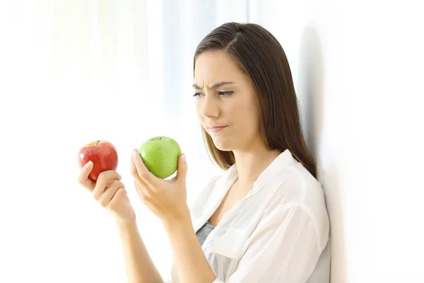 ผู้หญิงตัดสินใจระหว่างแอปเปิ้ลสีแดงและสีเขียว — ภาพถ่ายสต็อก