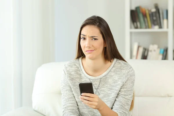 Suspicious woman holding phone looking at you — Stock Photo, Image