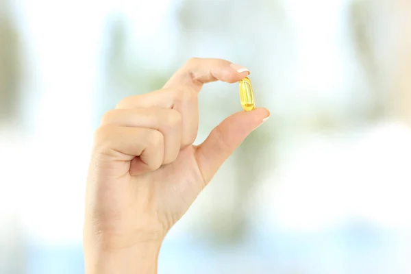 Mulher mão segurando uma pílula de vitamina amarela — Fotografia de Stock