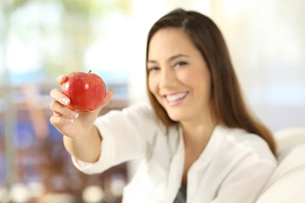 Mujer ofreciendo una manzana y mirando a la cámara — Foto de Stock