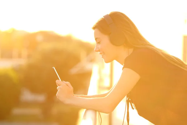 Lány segítségével egy okos telefon, egy erkély, naplementekor — Stock Fotó