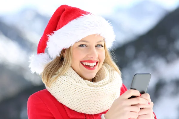 Щаслива жінка, дивлячись на тебе, тримає телефон у різдвяному — стокове фото