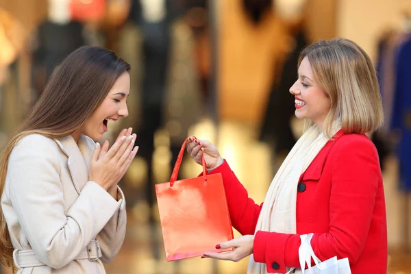 Comprador dando um presente a um amigo no inverno — Fotografia de Stock