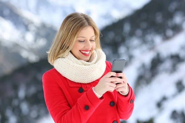 Женщина в красном с помощью смартфона зимой в горах — стоковое фото