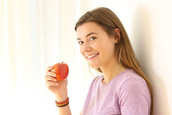 Teen holding an apple and looking at you — Stock Photo, Image