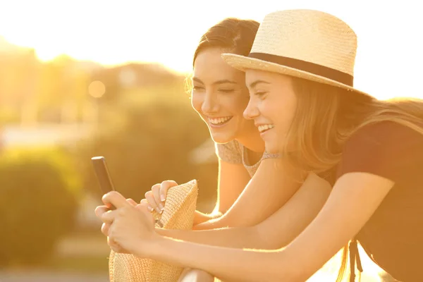 Dois amigos assistindo conteúdo on-line ao pôr do sol — Fotografia de Stock