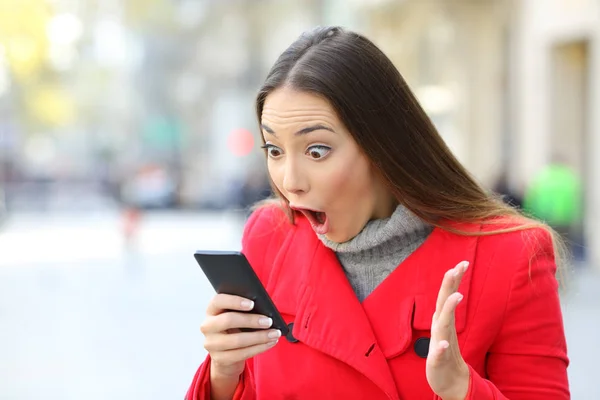 Mujer sorprendida leyendo noticias en línea en un teléfono — Foto de Stock