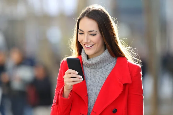 Mujer caminando y usando un teléfono inteligente en invierno — Foto de Stock