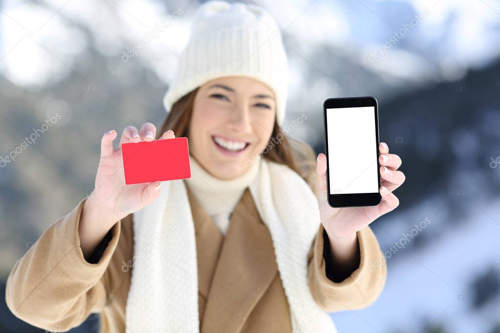 Woman showing a card and phone screen in winter