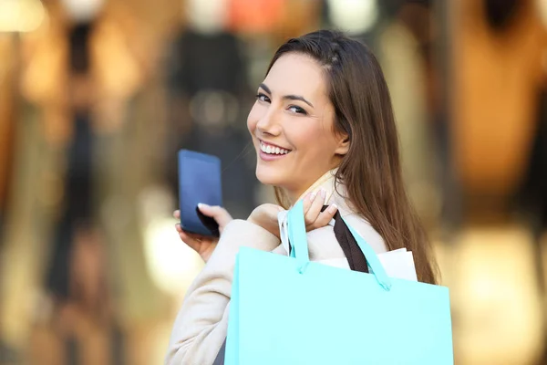 Shopper segurando telefone e sacos de compras olhando para você — Fotografia de Stock