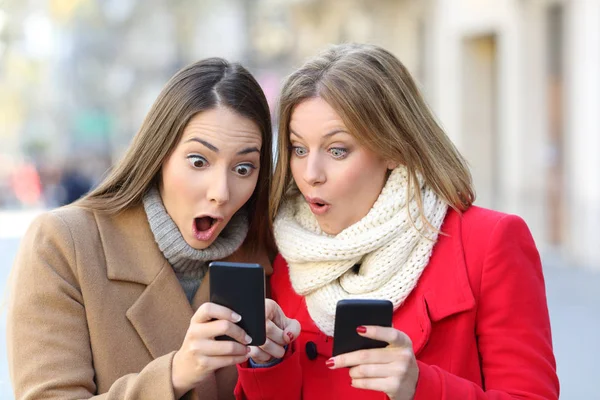 Dos mujeres sorprendidas encontrando contenido en los teléfonos —  Fotos de Stock