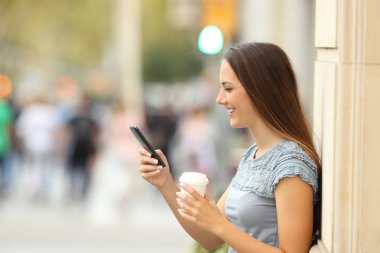 Sokakta bir akıllı telefon kullanan bir kız yan görünüm