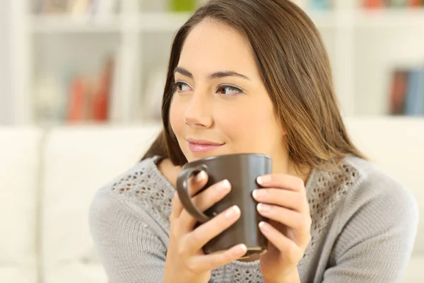 Pensive mulher segurando uma caneca de café olhando para o lado — Fotografia de Stock