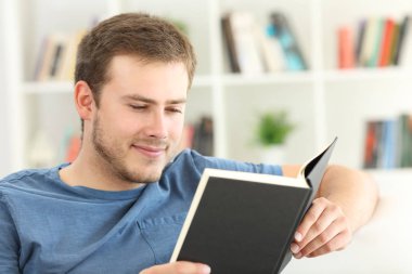 Evde bir kanepede kağıt kitap okurken erkek