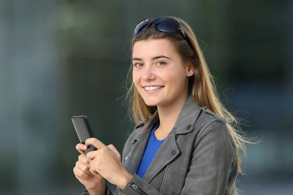 Mode kvinna med en telefon och tittar på dig på gatan — Stockfoto