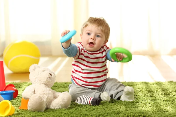 Bebê brincando com brinquedos em um tapete — Fotografia de Stock