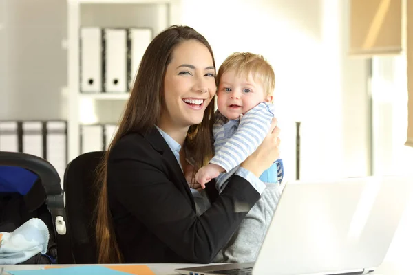 Щаслива робоча мати позує зі своєю дитиною в офісі — стокове фото