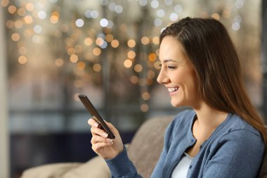 Işıklar içinde geçmiş ile evde bir akıllı telefon kullanan kız