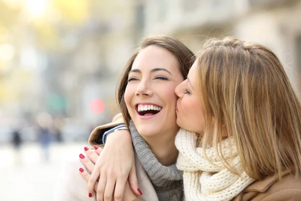 Menina beijando a seu amigo feliz no inverno — Fotografia de Stock