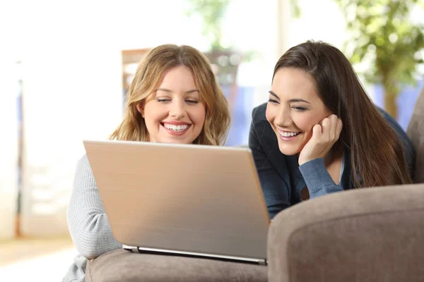 Twee huisgenoten kijken op lijn inhoud in een laptop thuis — Stockfoto