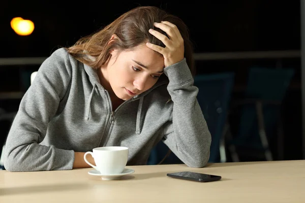 Triste adolescente à espera de uma mensagem de telefone em um bar — Fotografia de Stock