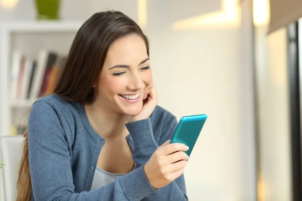 Mujer feliz leyendo texto en un smartphone en casa — Foto de Stock