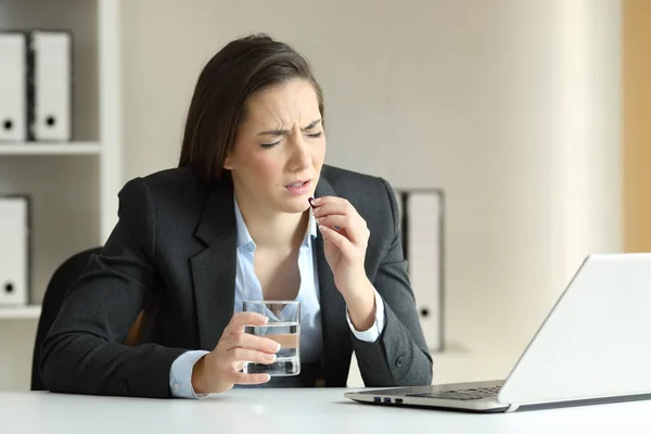 Плохая деловая женщина жалуется и принимает таблетки в офисе — стоковое фото