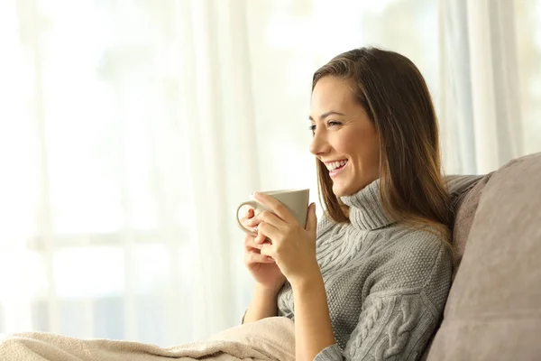 Pensive mulher segurando uma caneca de café relaxante em casa — Fotografia de Stock