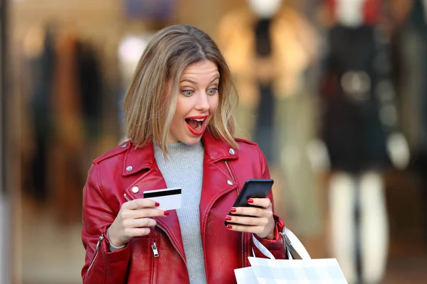 Förvånad shopper betala på nätet i ett köpcentrum — Stockfoto