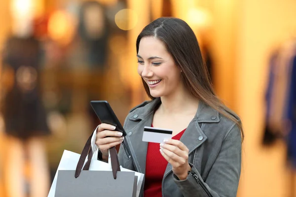 Shopper paying on line with credit card in a mall — Stock Photo, Image