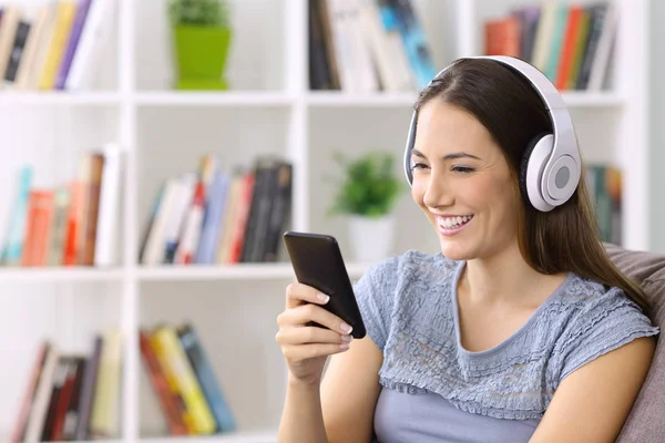 Flicka Lyssna på musik på linjen på en smart telefon — Stockfoto