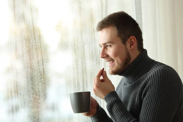 Happy man taking a pill in winter at home — Stock Photo, Image