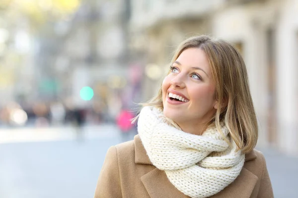 Lycklig kvinna tittar på sidan på gatan vintertid — Stockfoto