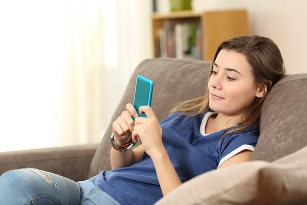 Adolescente usando um telefone inteligente azul em casa — Fotografia de Stock