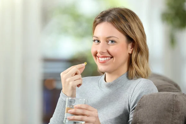 Mujer posando sosteniendo una píldora vitamínica lista para tomar —  Fotos de Stock