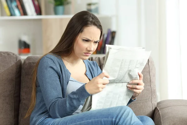 Mujer enojada leyendo un periódico en un sofá —  Fotos de Stock