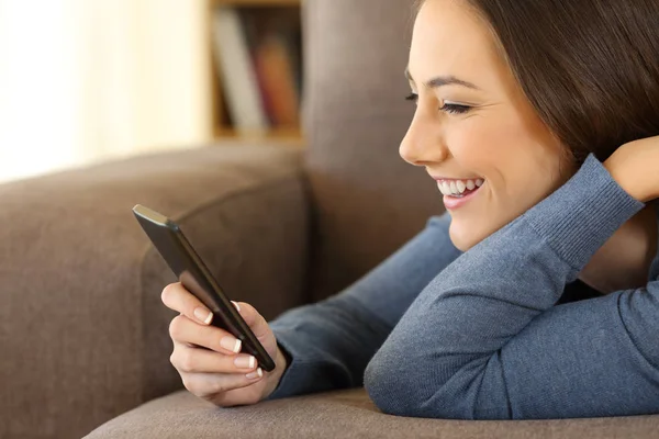 Flicka som läser meddelanden i en mobiltelefon hemma — Stockfoto