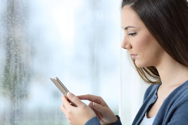 Donna seria che utilizza uno smartphone un giorno di pioggia — Foto Stock