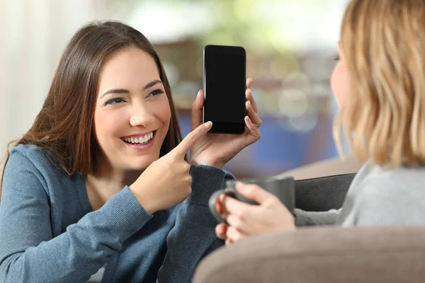 Menina mostrando uma tela de telefone em branco para um amigo em casa — Fotografia de Stock