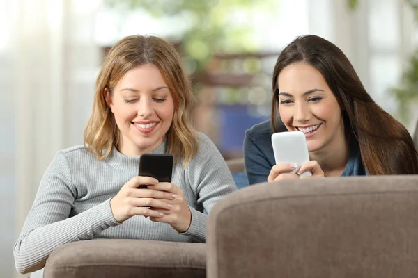 Colegas de quarto usando dois telefones inteligentes em casa — Fotografia de Stock