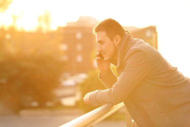 Kışın bir balkonda telefonda konuşan adam