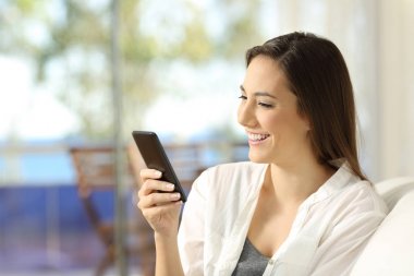 Bir apartman dairesinde bir akıllı telefon kullanan kadın