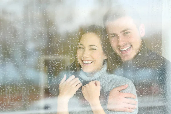 Freudiges Paar blickt an einem regnerischen Tag durch ein Fenster — Stockfoto