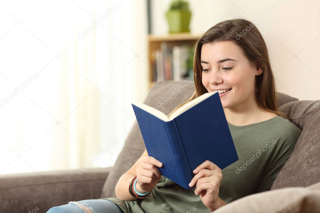 Teenager reading a book on a sofa at home