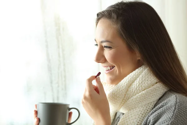 Mujer feliz tomando una píldora en un día lluvioso de invierno —  Fotos de Stock