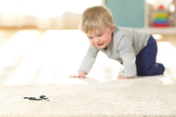 Baby in danger crawling towards a scissors — Stock Photo, Image