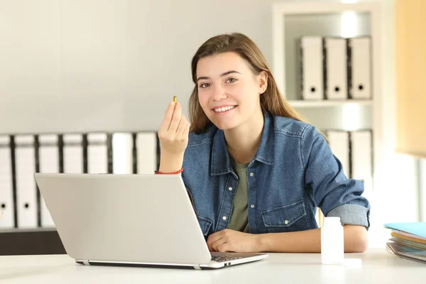 Estagiário mostrando uma pílula vitamínica no escritório — Fotografia de Stock