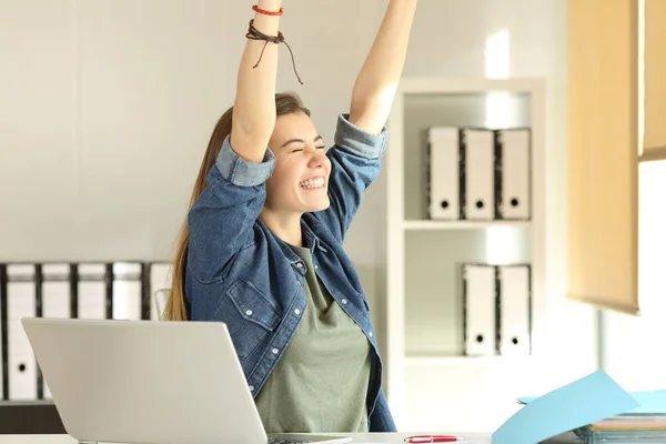 Estagiário satisfeito levantando armas no escritório — Fotografia de Stock